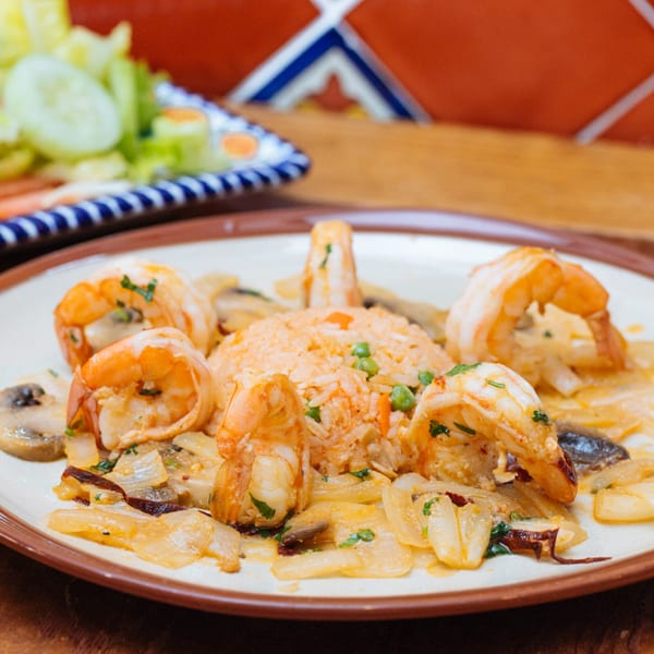 Frida Cantina's shrimp dish with rice, mushrooms, and onions, with a side salad.