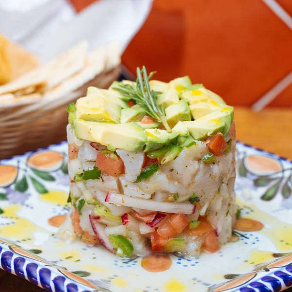 Frida Cantina's ceviche with diced fish, tomatoes, and avocado, garnished with rosemary on a decorative plate.