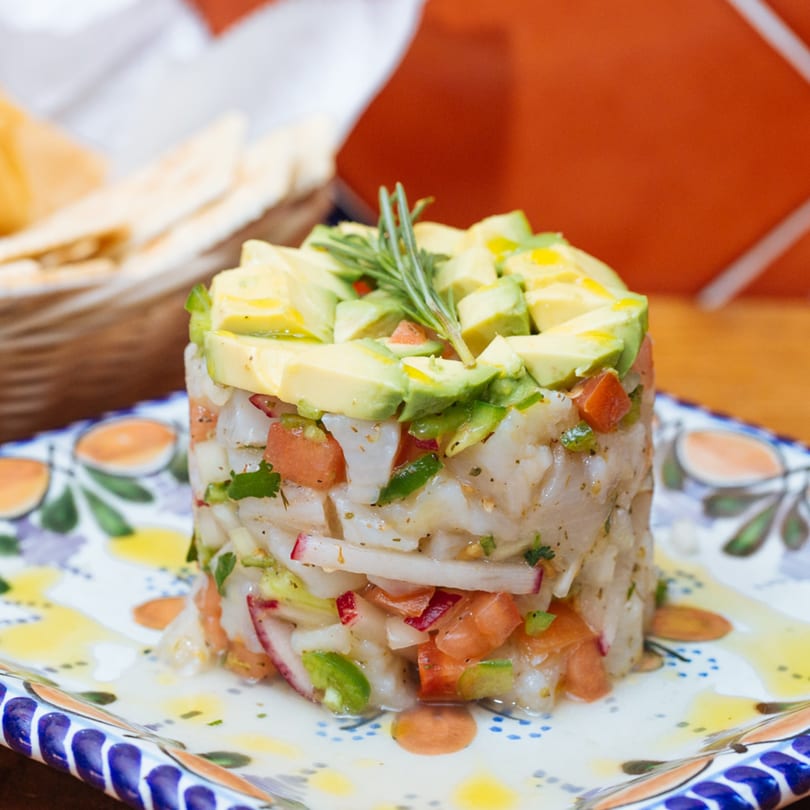 Frida Cantina's ceviche with diced fish, tomatoes, and avocado, garnished with rosemary on a decorative plate.