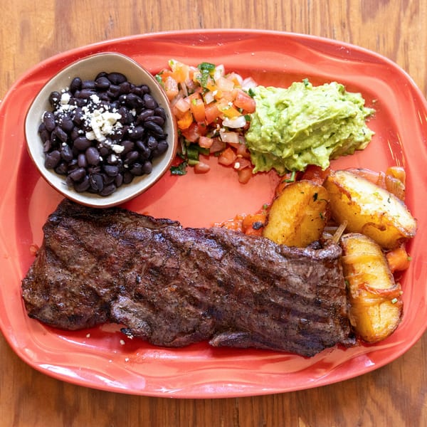 Frida Cantina's Mexican skirt steak with black beans, guacamole, pico de gallo, and roasted potatoes.