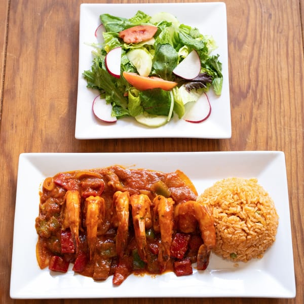Frida Cantina's shrimp dish with rice and a side salad on a wooden table.